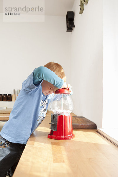 Junge öffnet Gummiballmaschine in der Küche