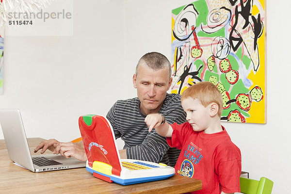 Vater und Sohn bei der Arbeit an Laptops