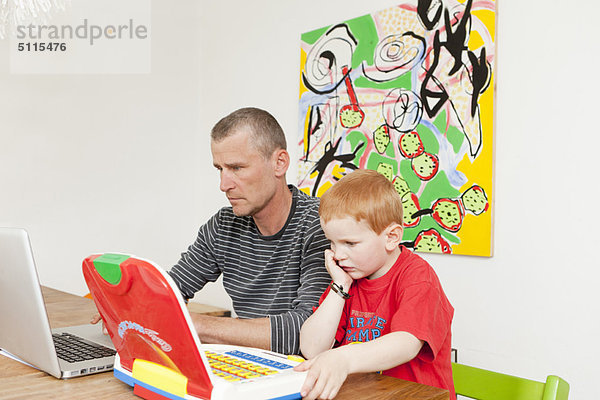 Vater und Sohn bei der Arbeit an Laptops