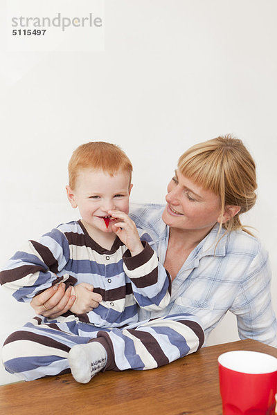 Mutter und Sohn im Pyjama bei Tisch