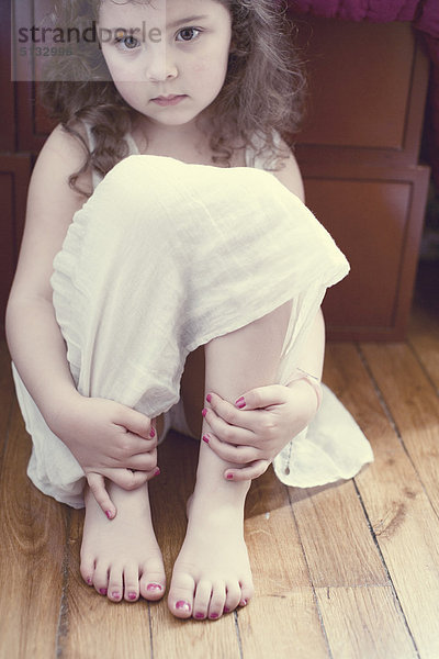 Kleines Mädchen im Kleid  Knie umarmend  Porträt