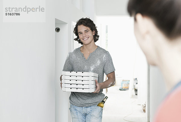 Junger Mann mit Pizzakarton in renovierter Wohnung