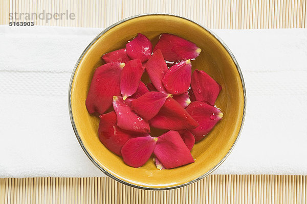 Nahaufnahme der Keramikschale mit Rosenblättern und Wasser auf dem Handtuch