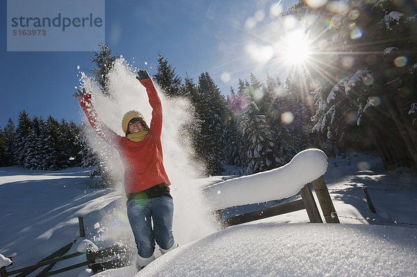 Österreich  Salzburger Land  Flachau  Junge Frau mit Schneeschuhen im Schnee springen