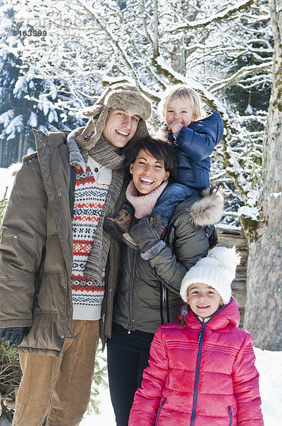 Österreich  Salzburger Land  Flachau  Ansicht der Familie im Schnee stehend  lächelnd  Portrait