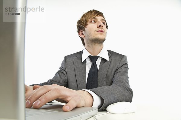 Junger Geschäftsmann bei der Arbeit am Laptop vor weißem Hintergrund