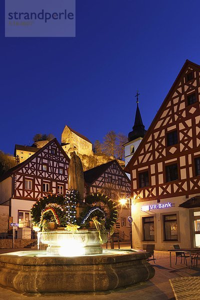 Deutschland  Bayern  Franken  Oberfranken  Fränkische Schweiz  Pottenstein  Osterbrunnen  Stadtansicht mit Osterdekoration auf Brunnen bei Nacht