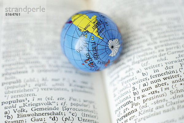 Deutschland  Nahaufnahme der Erdkugel auf offenem Wörterbuch