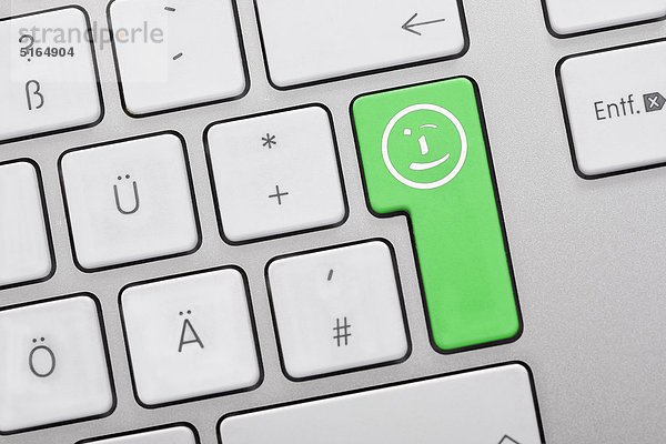 Nahaufnahme von Computertasten mit Smiley-Symbol auf grüner Taste