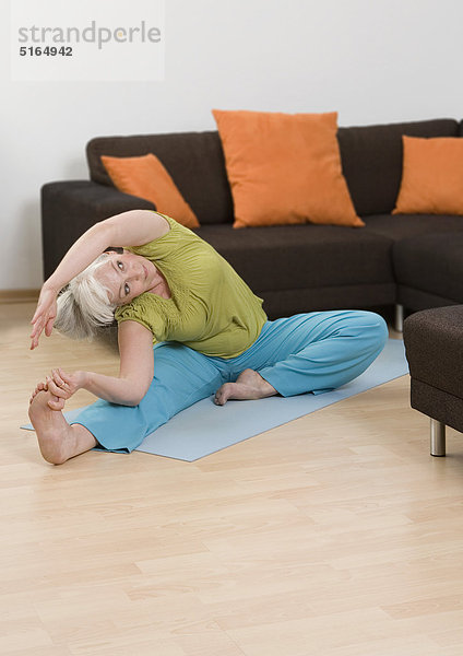 Frau beim Yoga in der Nähe des Sofas zu Hause