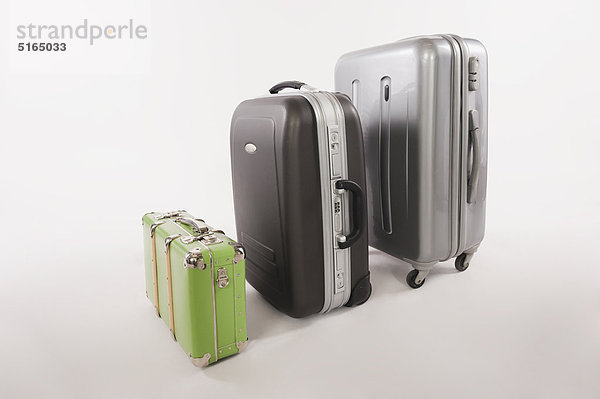 Verschiedene Koffer und Gepäckstücke in einer Reihe vor weißem Hintergrund