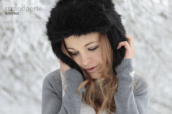 Junge Frau mit Mütze im Schnee