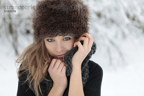 Junge Frau mit Schal und Mütze im Schnee