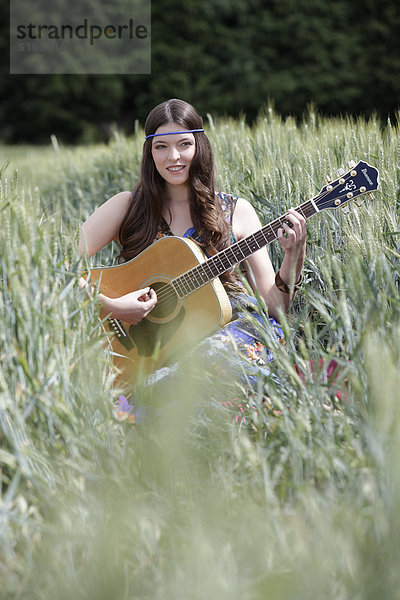 Junge Frau mit Gitarre im Kornfeld