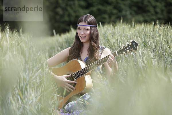 Junge Frau mit Gitarre im Kornfeld