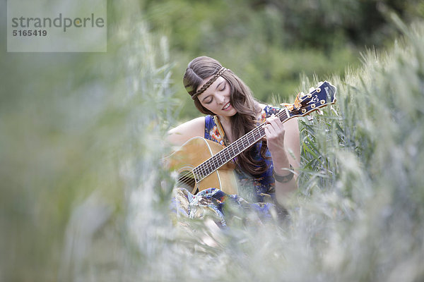 Junge Frau mit Gitarre im Kornfeld