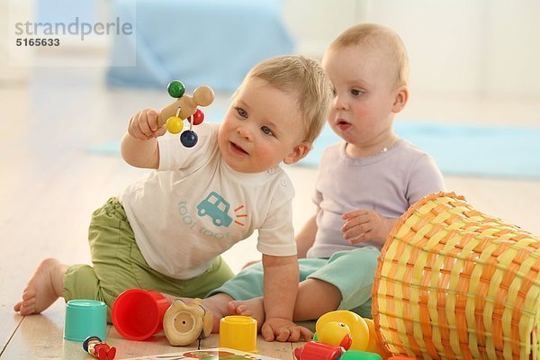 Zwei Babys spielen auf dem Fußboden