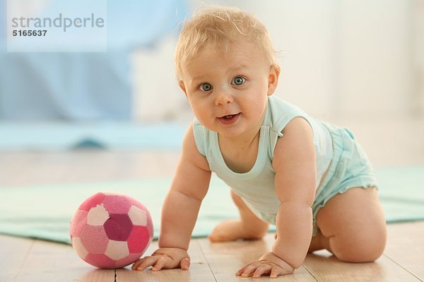 Baby mit einem Ball auf dem Fußboden