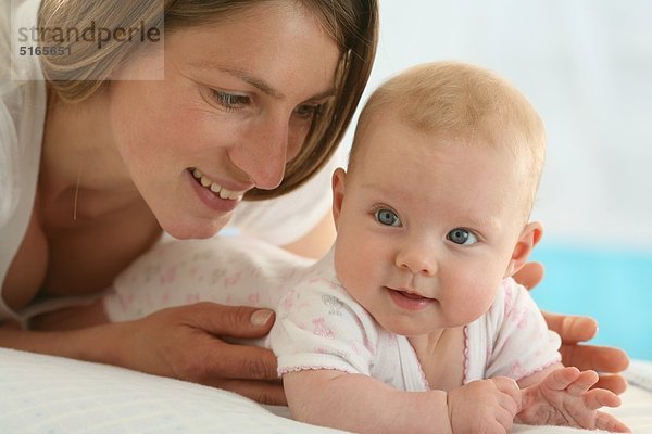 Mutter liegt mit Baby auf einer Decke