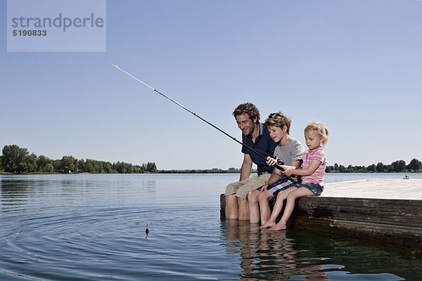 Vater und Kinder beim Angeln am Steg