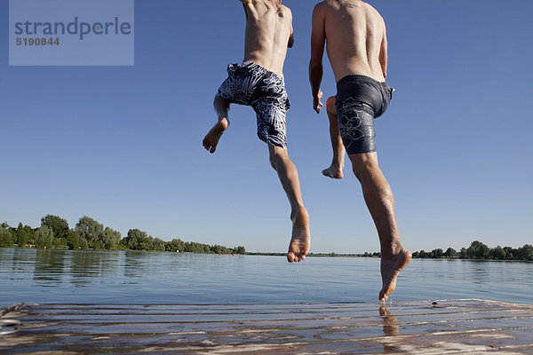 Vater und Sohn springen in den See