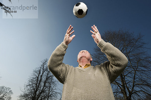 Älterer Mann spielt mit Fußball