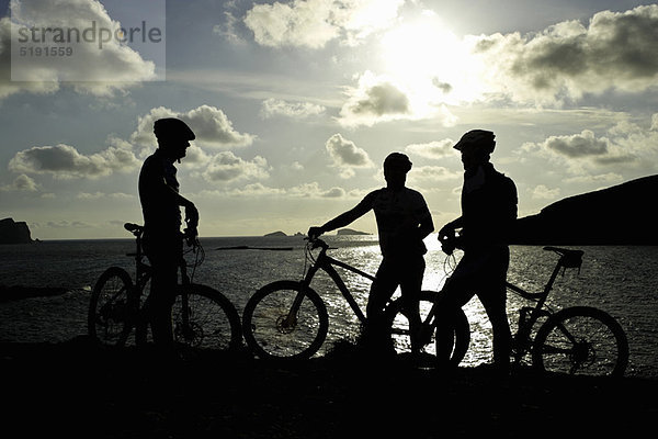 Silhouetten von Mountainbikern am See