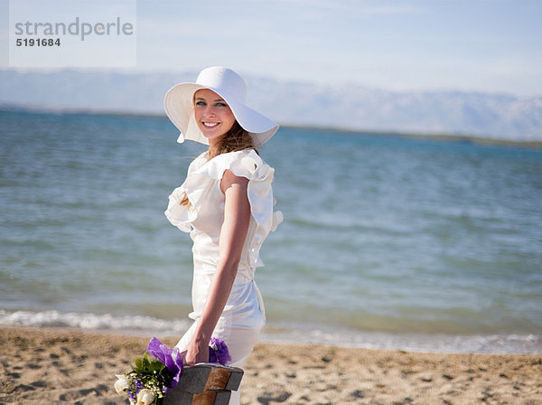 Braut mit Blumenstrauß am Strand