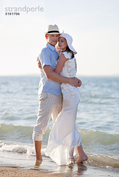 Neuvermähltes Paar umarmt am Strand