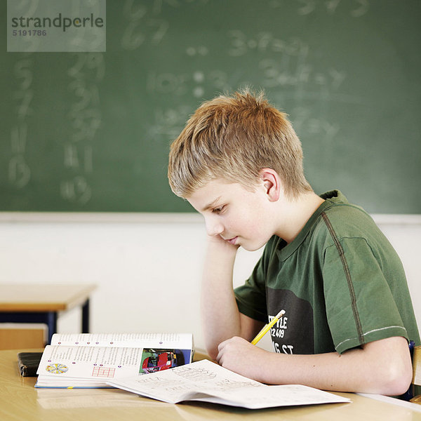 Junge studiert am Schreibtisch im Klassenzimmer