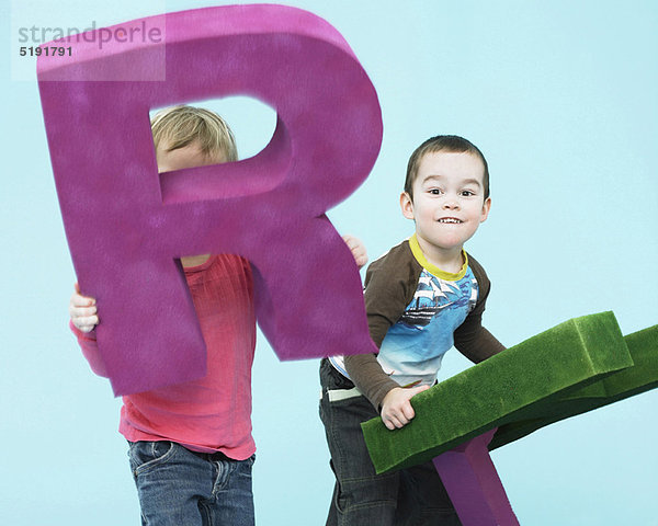 Kleinkinder spielen mit übergroßen Buchstaben