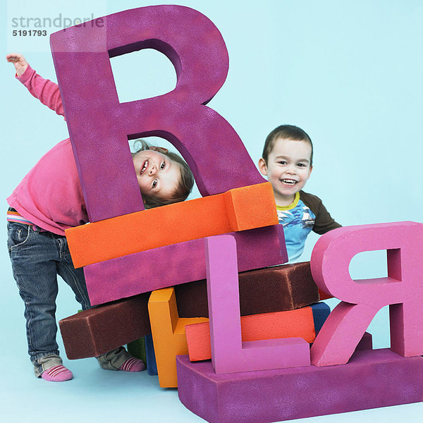 Kleinkinder spielen mit übergroßen Buchstaben