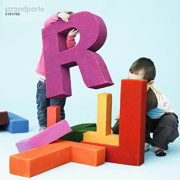Kleinkinder spielen mit übergroßen Buchstaben