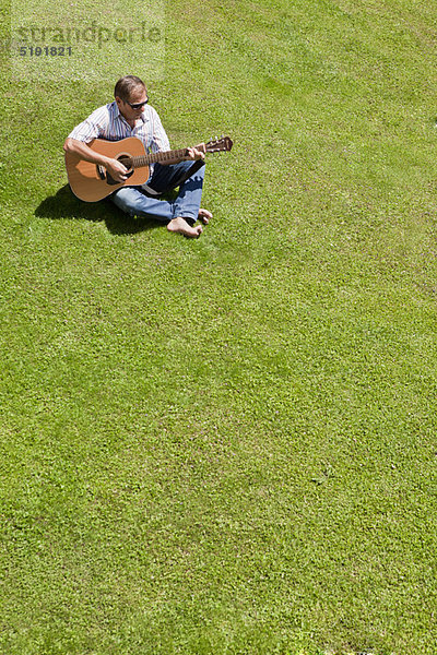 Mann spielt Gitarre im Gras