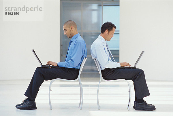 Geschäftsleute mit Laptops in der Lobby