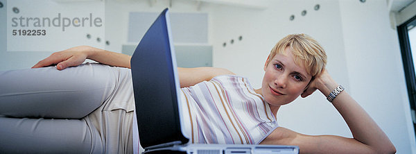 Frau auf dem Boden liegend mit Laptop