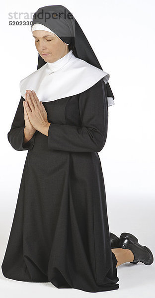 Nonne in Schwesterntracht  Betet knieend