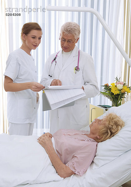 Arzt und Krankenschwester bei älterer Patientin im Krankenhaus