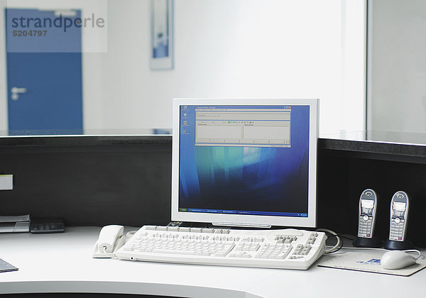 Flachbildschirm  Tastatur und Telefone auf Schreibtisch