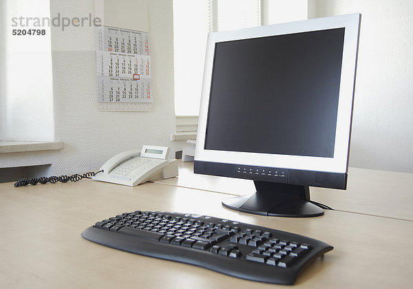 Flachbildschirm  Tastatur und Telefon auf Schreibtisch