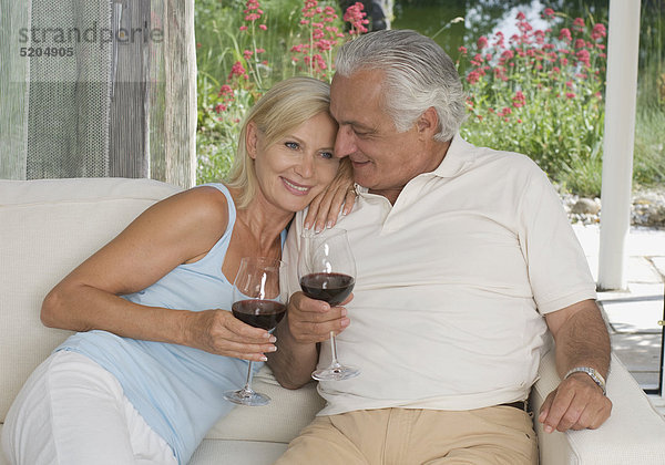 Älteres Paar  sitzen auf Sofa  trinken Rotwein