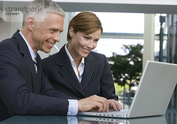Business-Paar  mittleres Alter  sitzen in Bürogebäude an Laptop