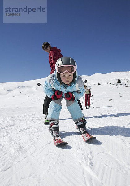 Familie beim Skifahren  kleines Mädchen fährt Vater durch die Beine