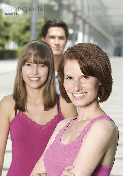Zwei Studentinnen und Student stehen hintereinander