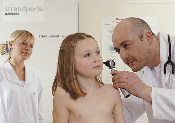 Kinderarzt sieht Mädchen mit Otoskop ins Ohr
