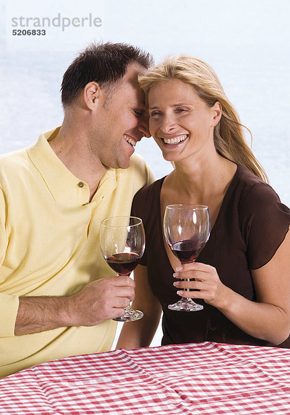 Paar  sitzen am Wasser  trinken Rotwein