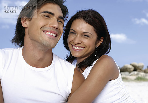 Paar in weißen Shirts an Strand  lachen  Halbporträt