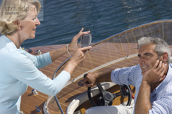 Seniorenpaar auf Motorboot  sie fotografiert ihn