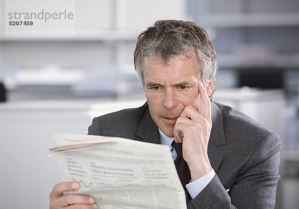 Mann liest im Büro Zeitung  angespannt