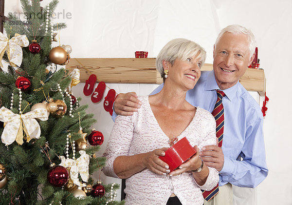 Seniorenpaar neben Weihnachtsbaum